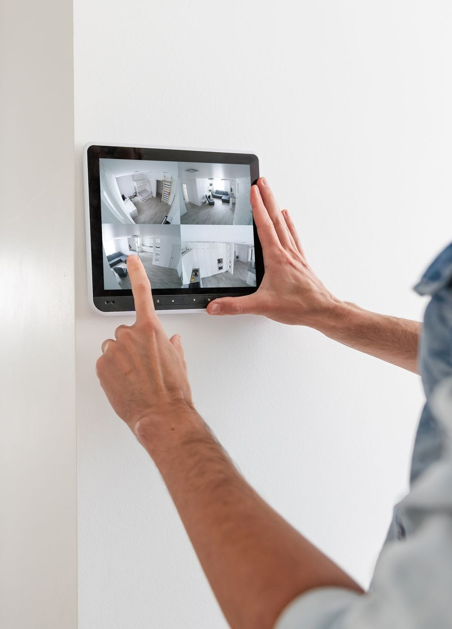 Person using a wall-mounted tablet to view and control a home security camera system