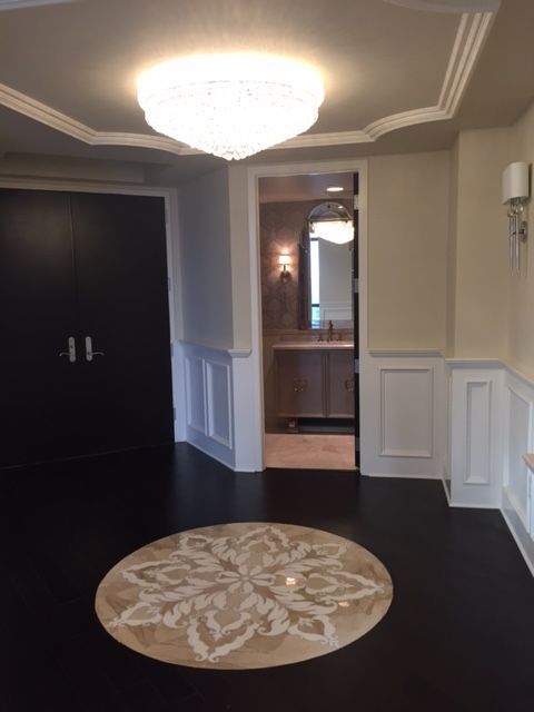 A hallway with a round rug and a chandelier