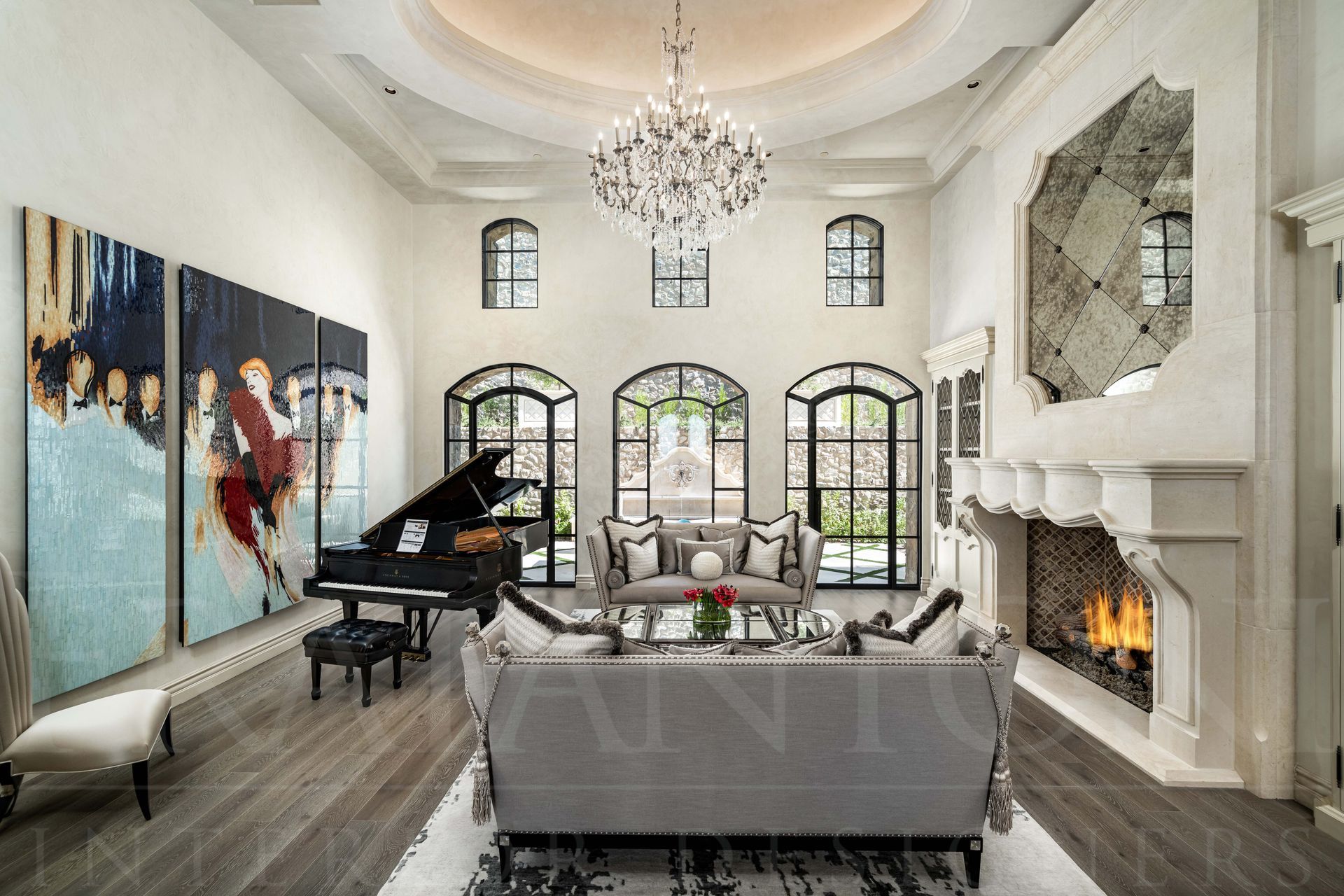 A luxurious, French designed high-ceilinged formal living room with a grand piano, grey sofas, a large fireplace, and modern wall art.