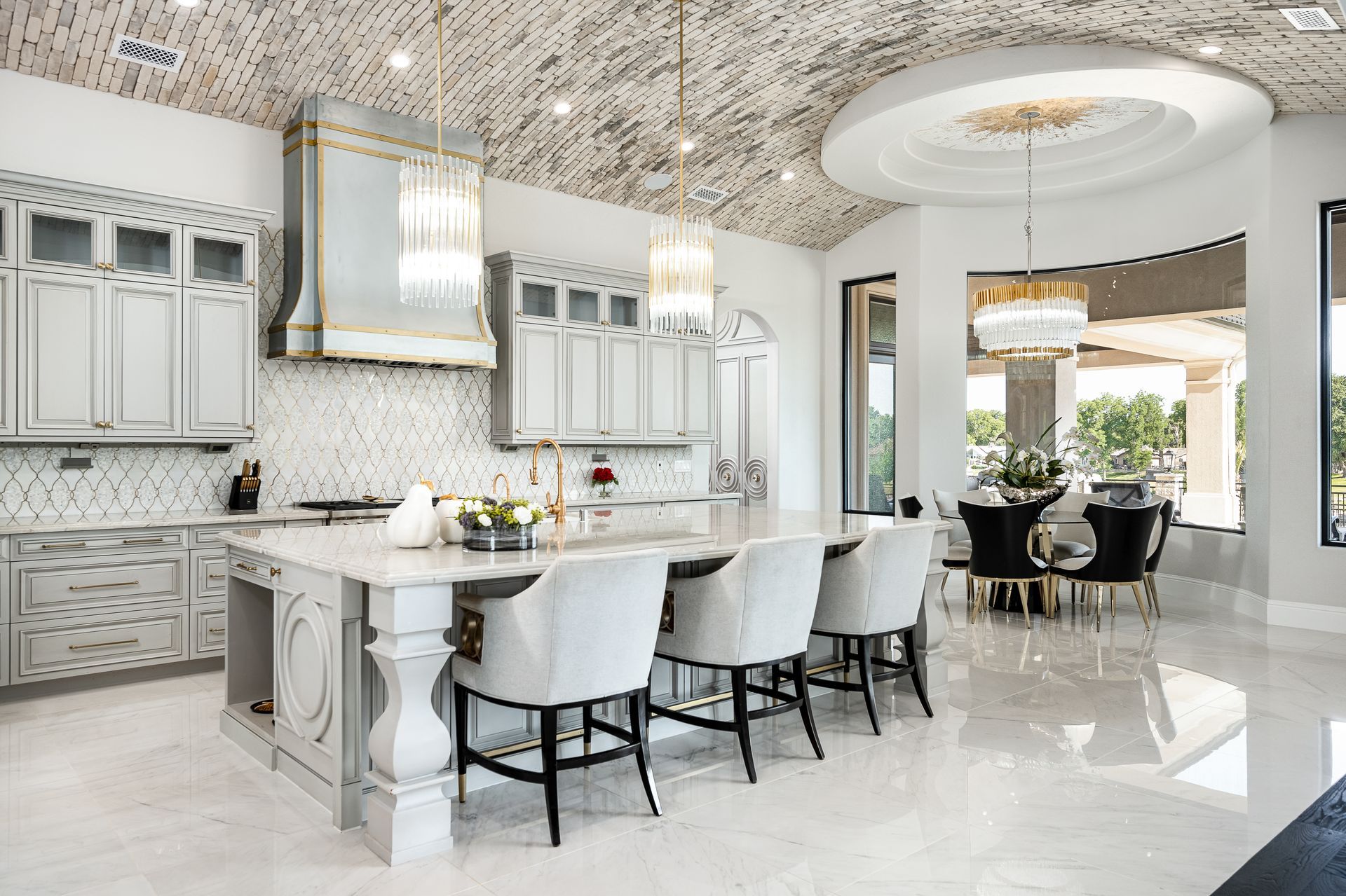 A kitchen with white cabinets , a large island , and a dining room.