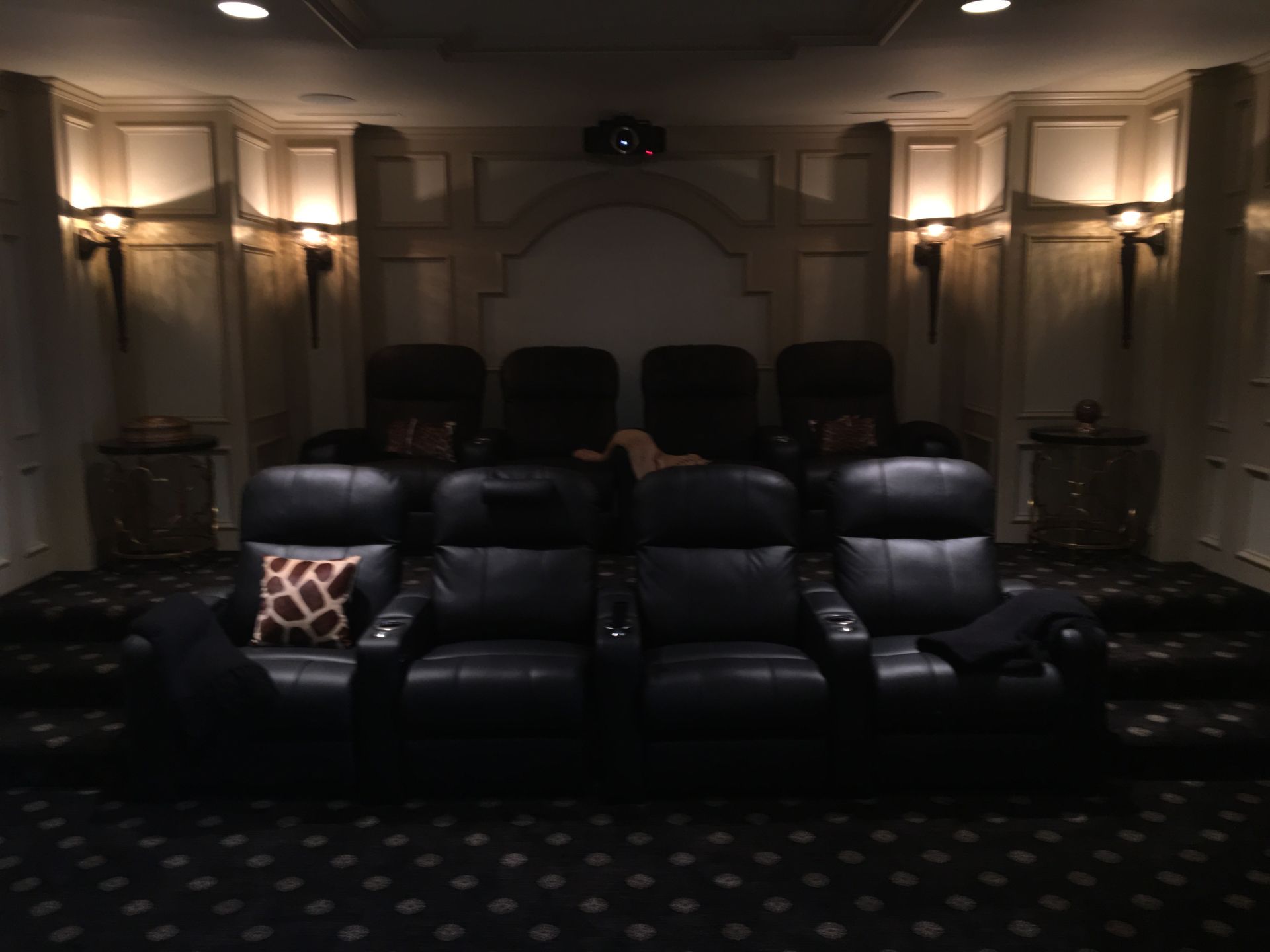 A movie theater with black leather seats and a giraffe pillow
