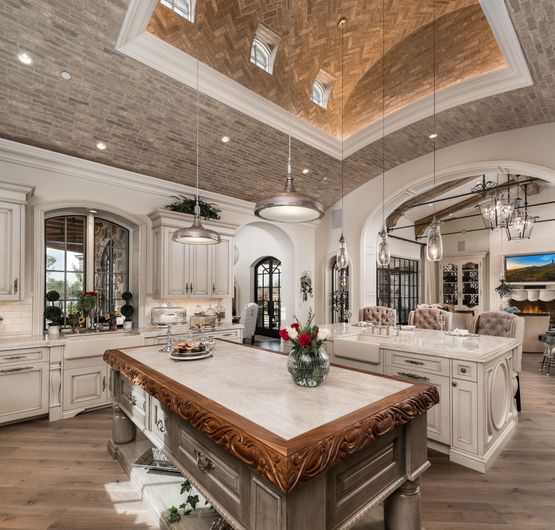 French villa kitchen interior design with dual islands, brick barrel ceiling and custom furnishings.