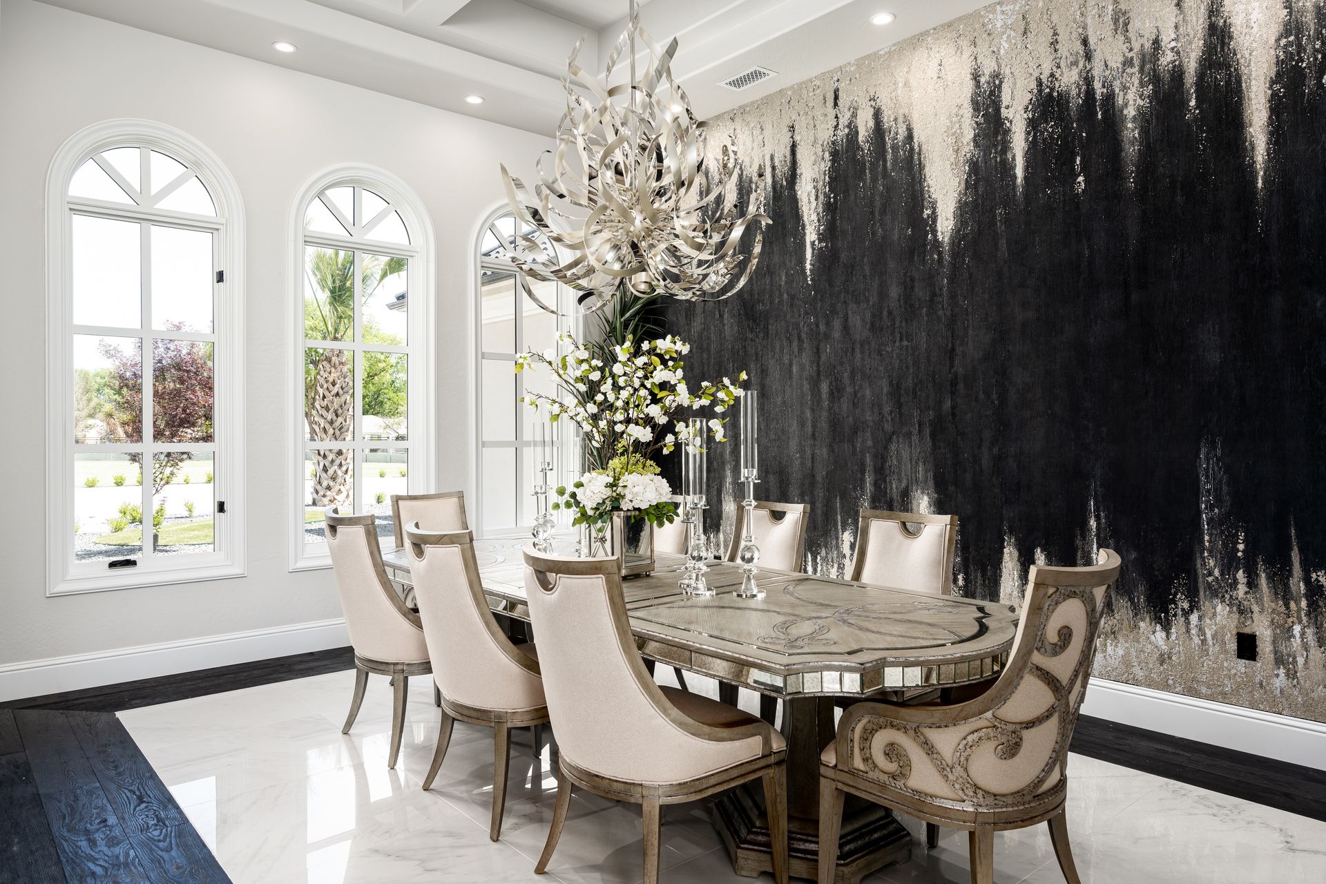A dining room with a table and chairs and a large painting on the wall.