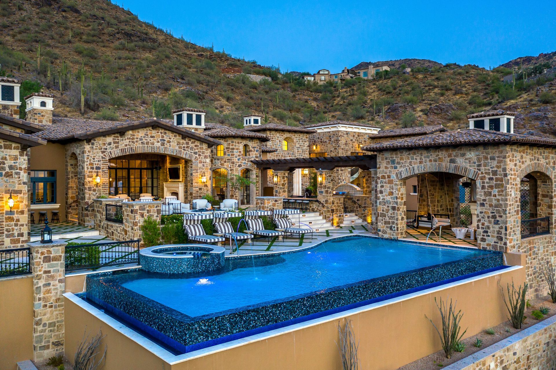 A large stone house with a large swimming pool in front of it.