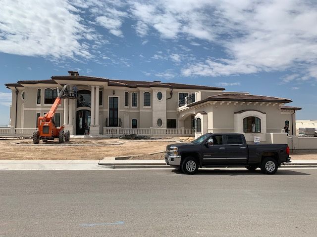 A truck is parked in front of a large house under construction