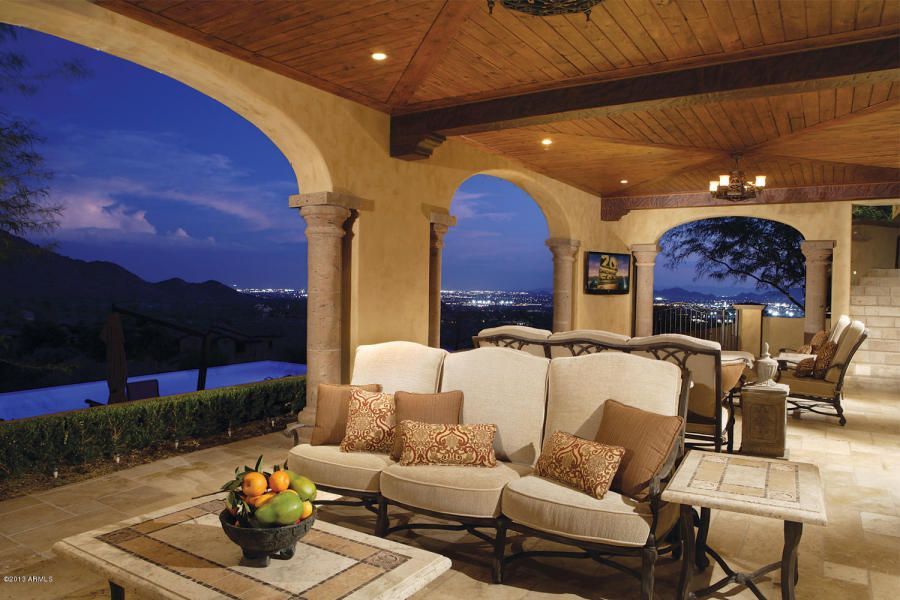A patio with a couch and a table with a bowl of fruit on it