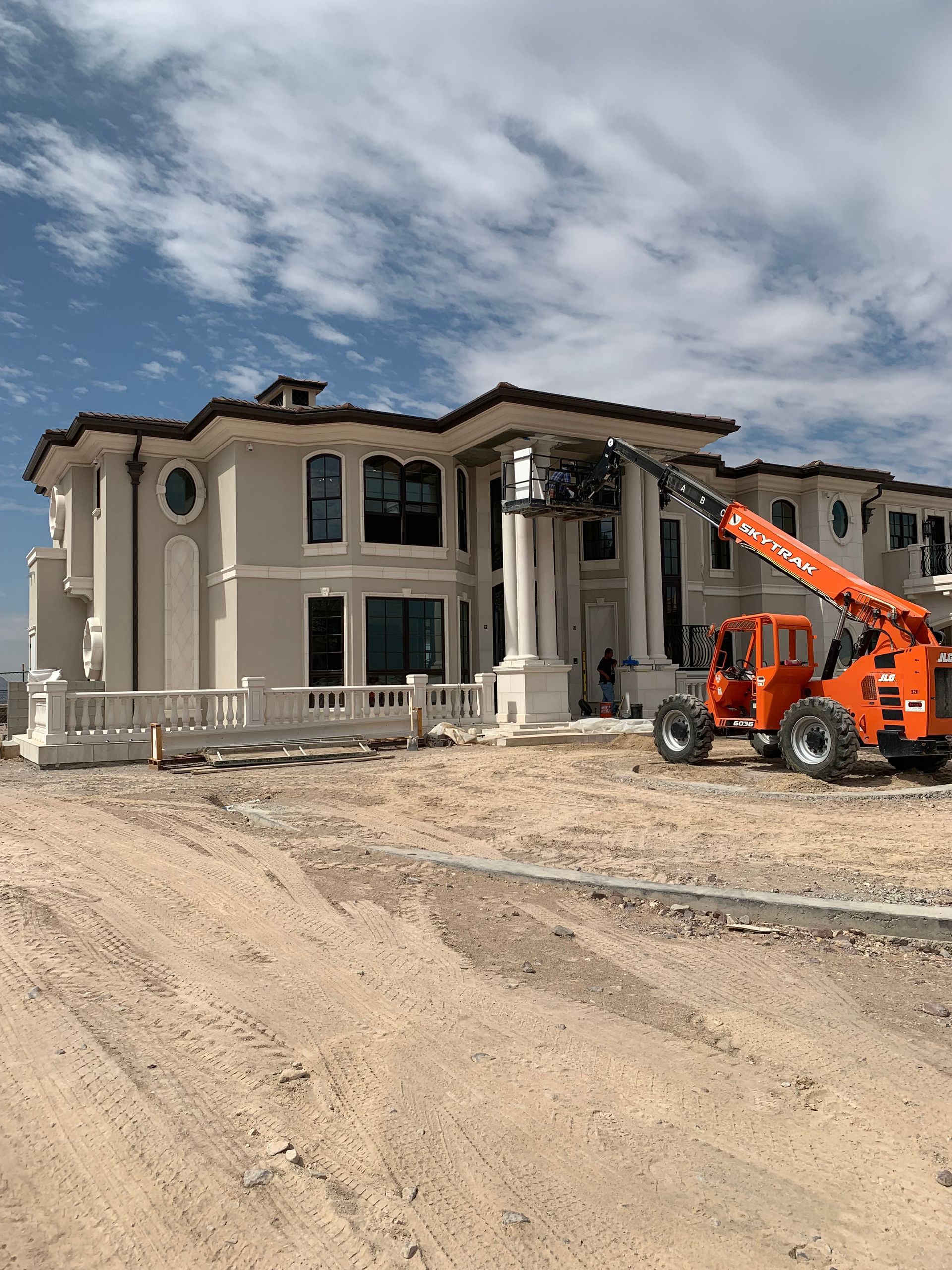 A large house is being built and a crane is parked in front of it.