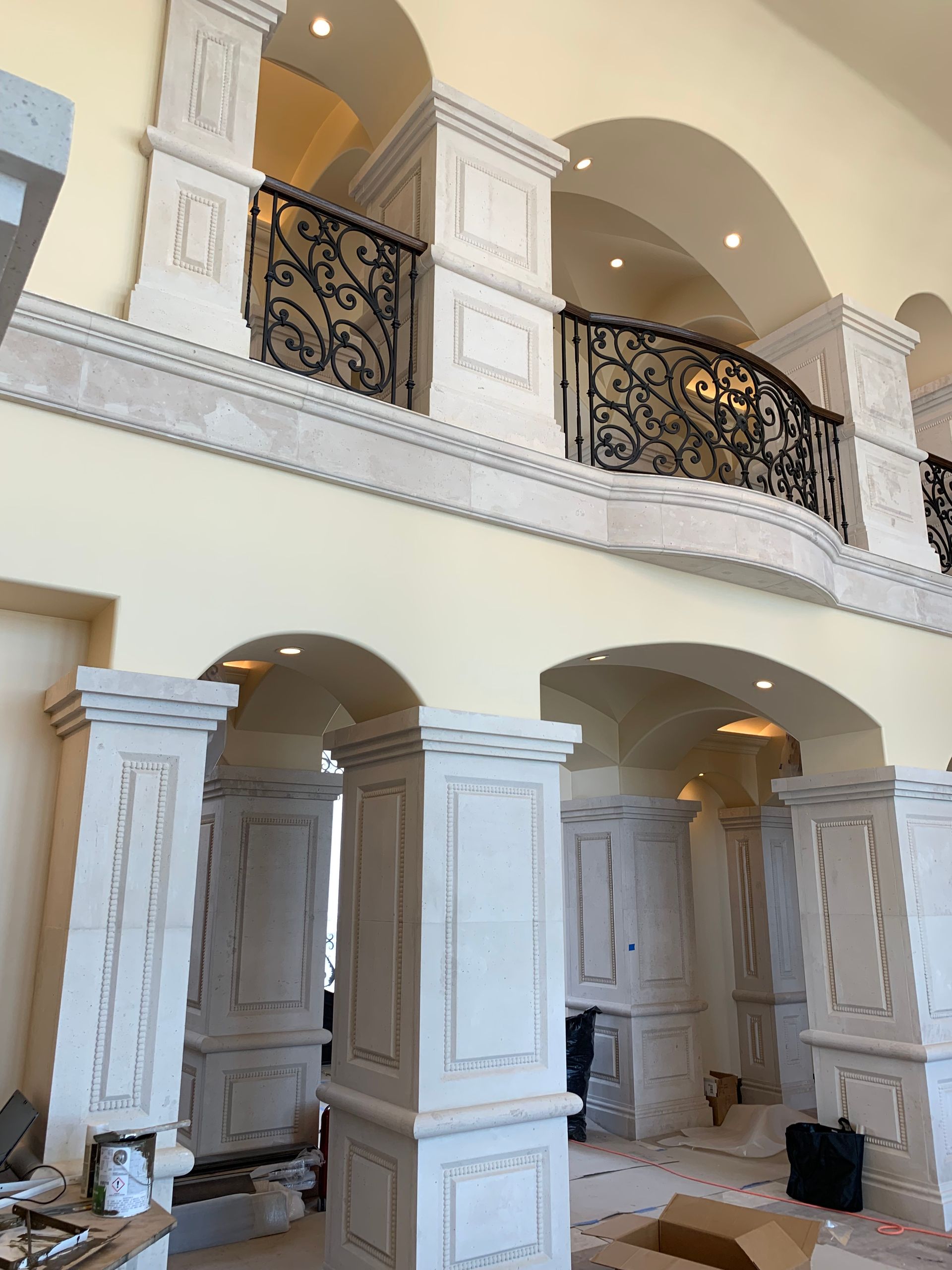 A room with columns and a balcony with a wrought iron railing