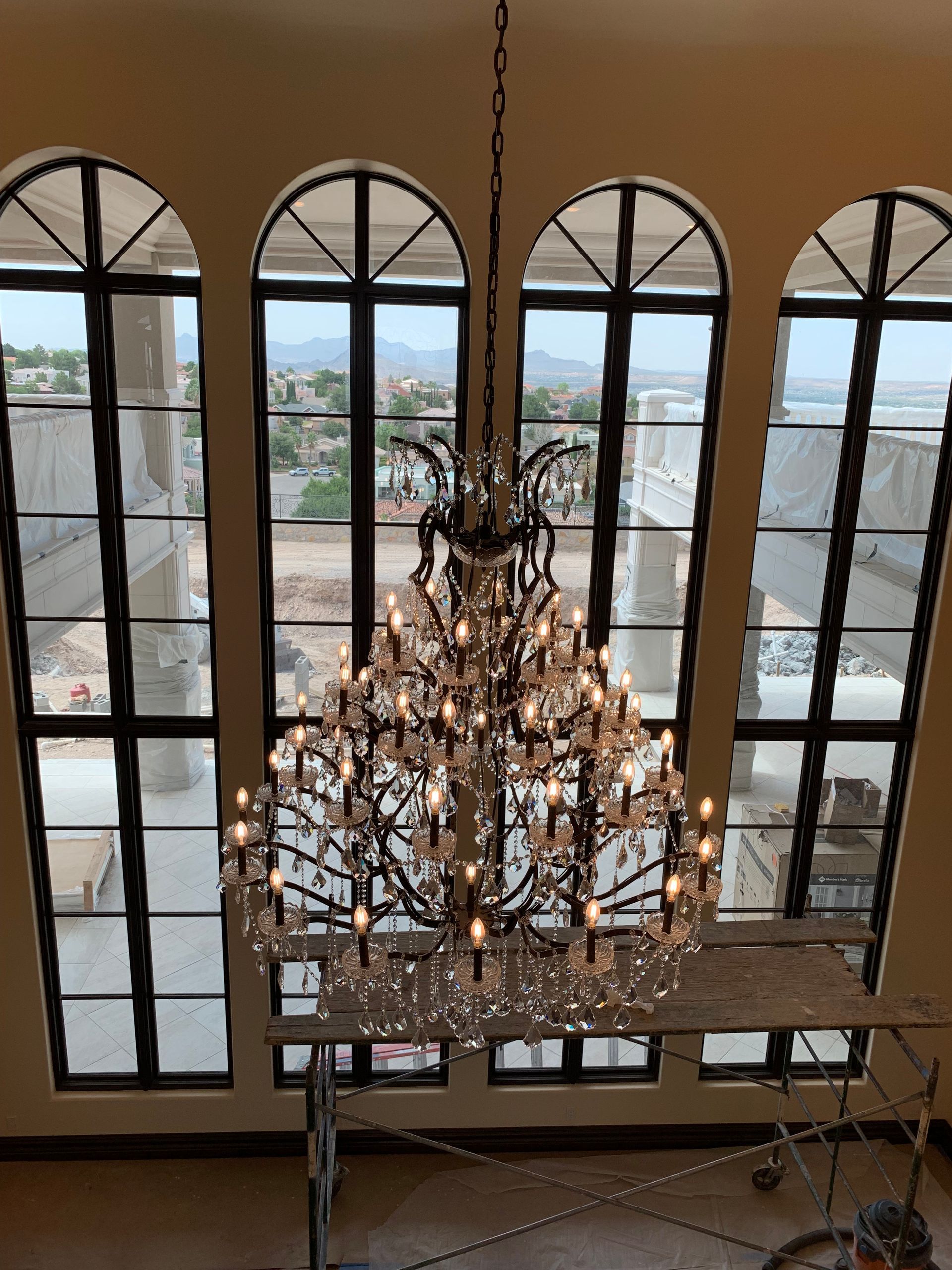 A large chandelier is hanging from the ceiling in front of a large window.