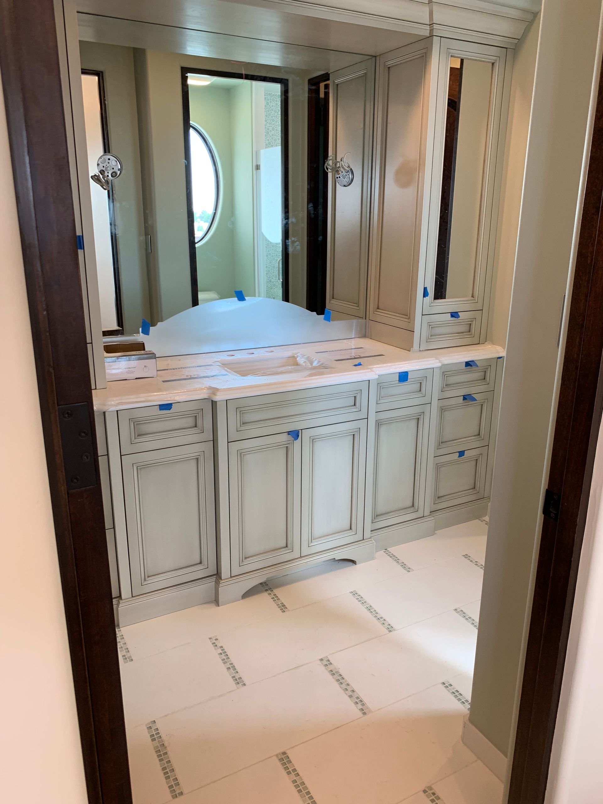 A bathroom with white cabinets and a large mirror
