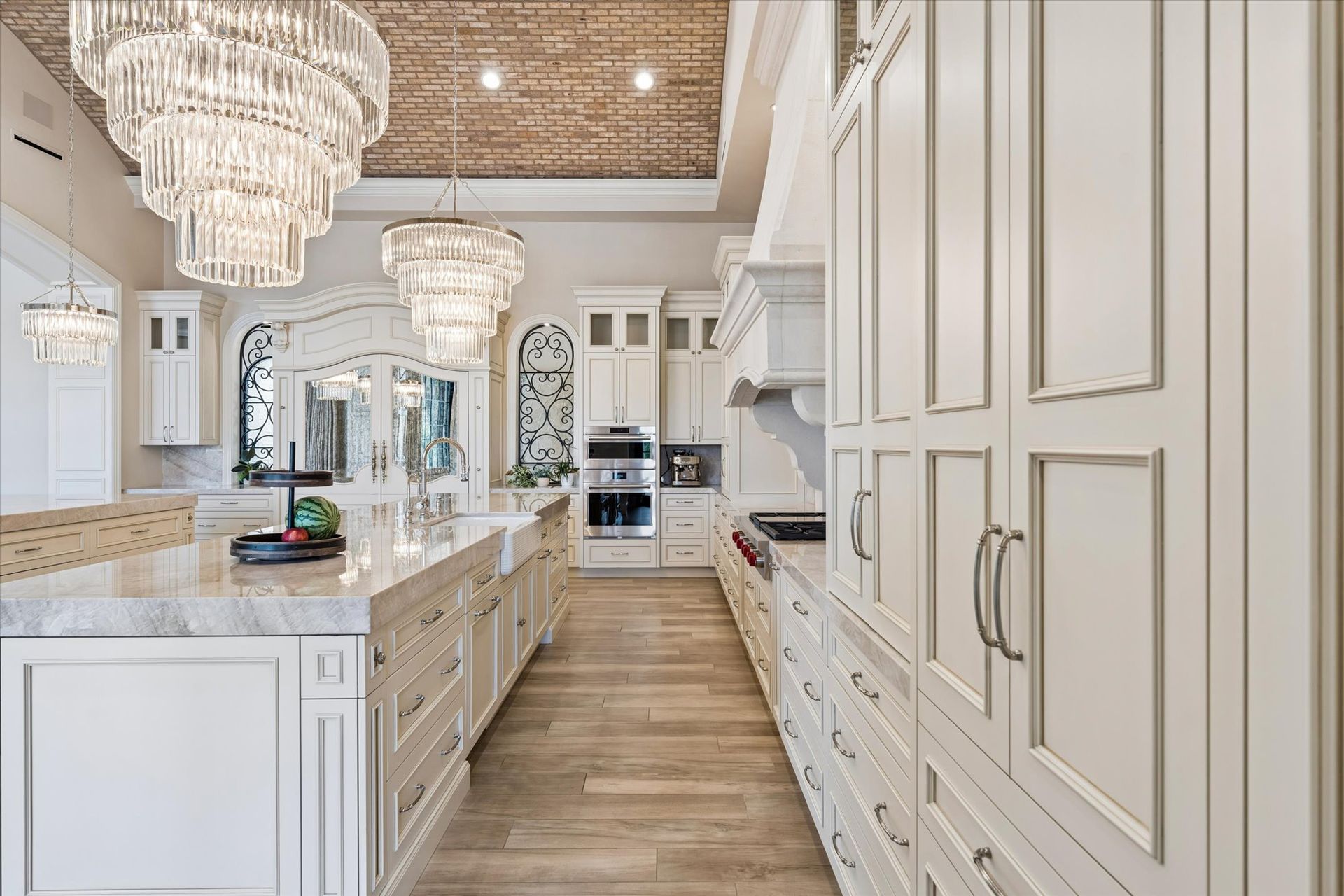 Luxury kitchen with dual marble island, crystal chandeliers, and wood floor