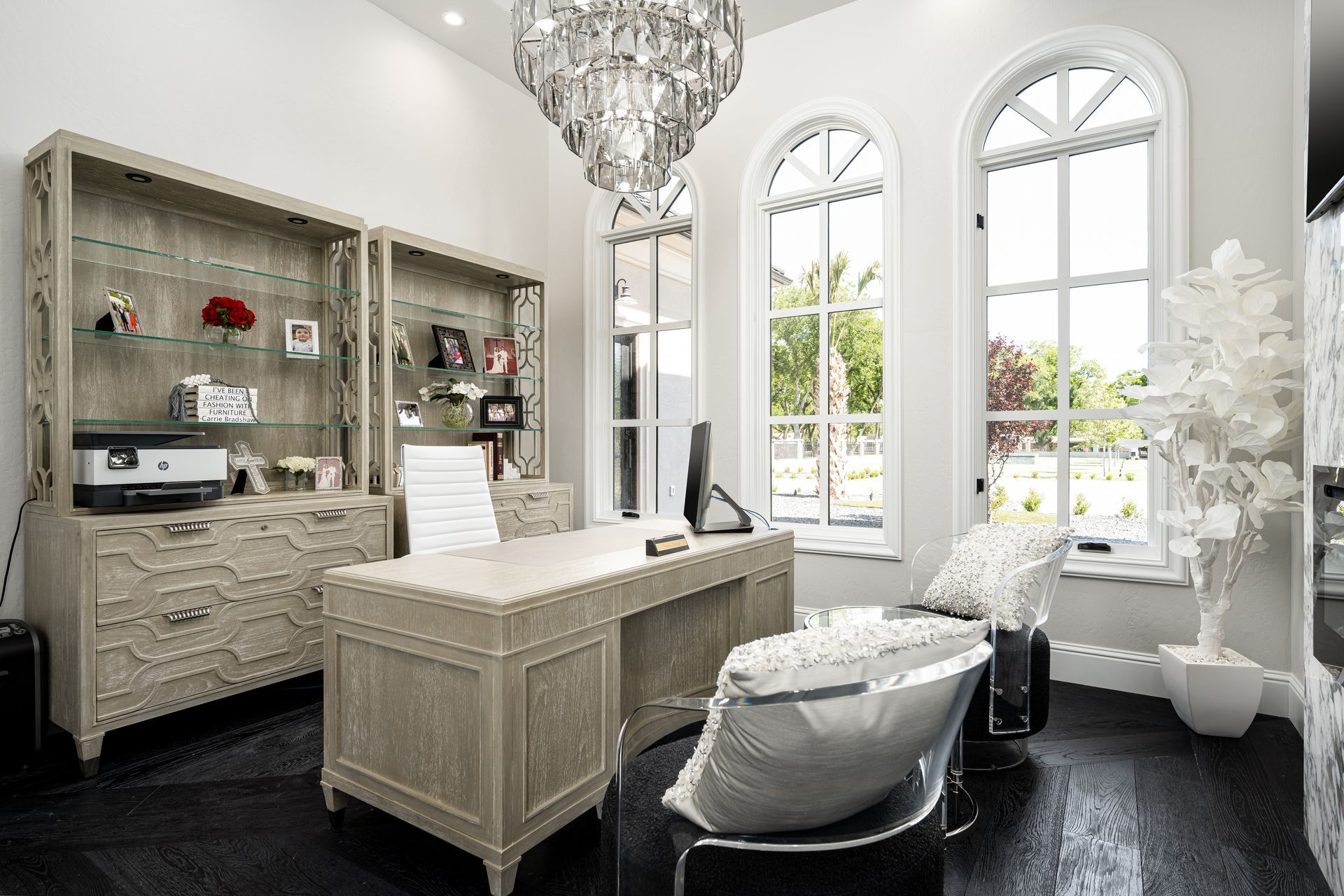 A home office with a desk , chair , and chandelier.