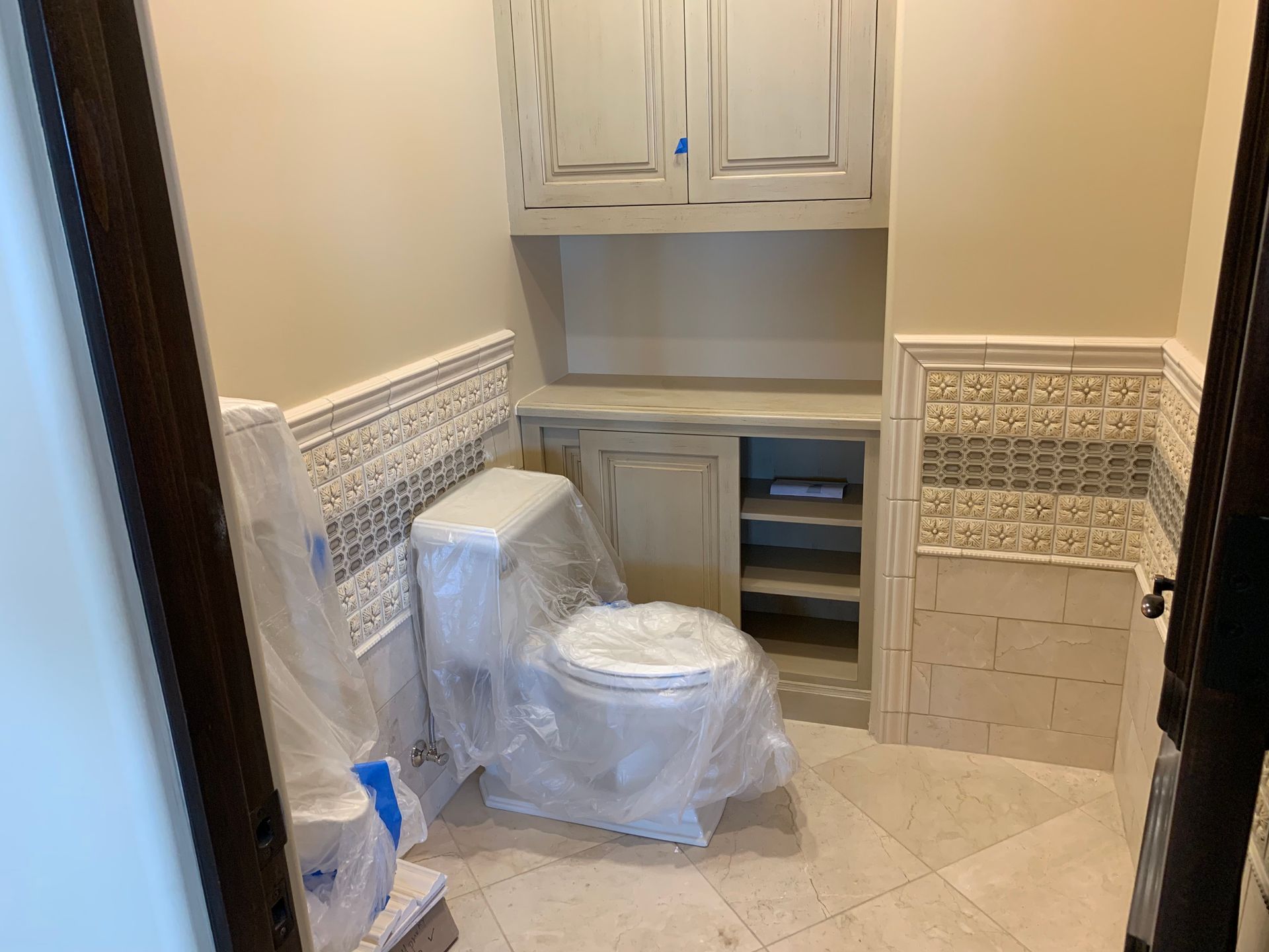 A bathroom with a toilet and cabinets covered in plastic.