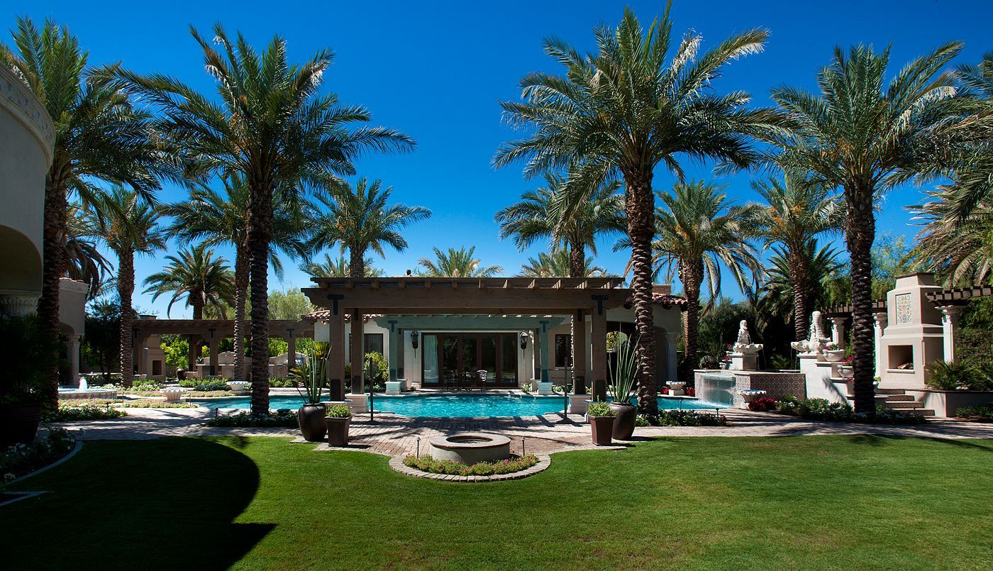 A large house with a swimming pool surrounded by palm trees