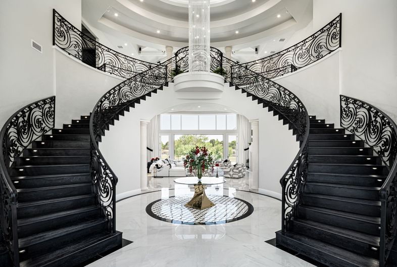 Modern dual staircase interior design, high contrast with chandelier and marble flooring.