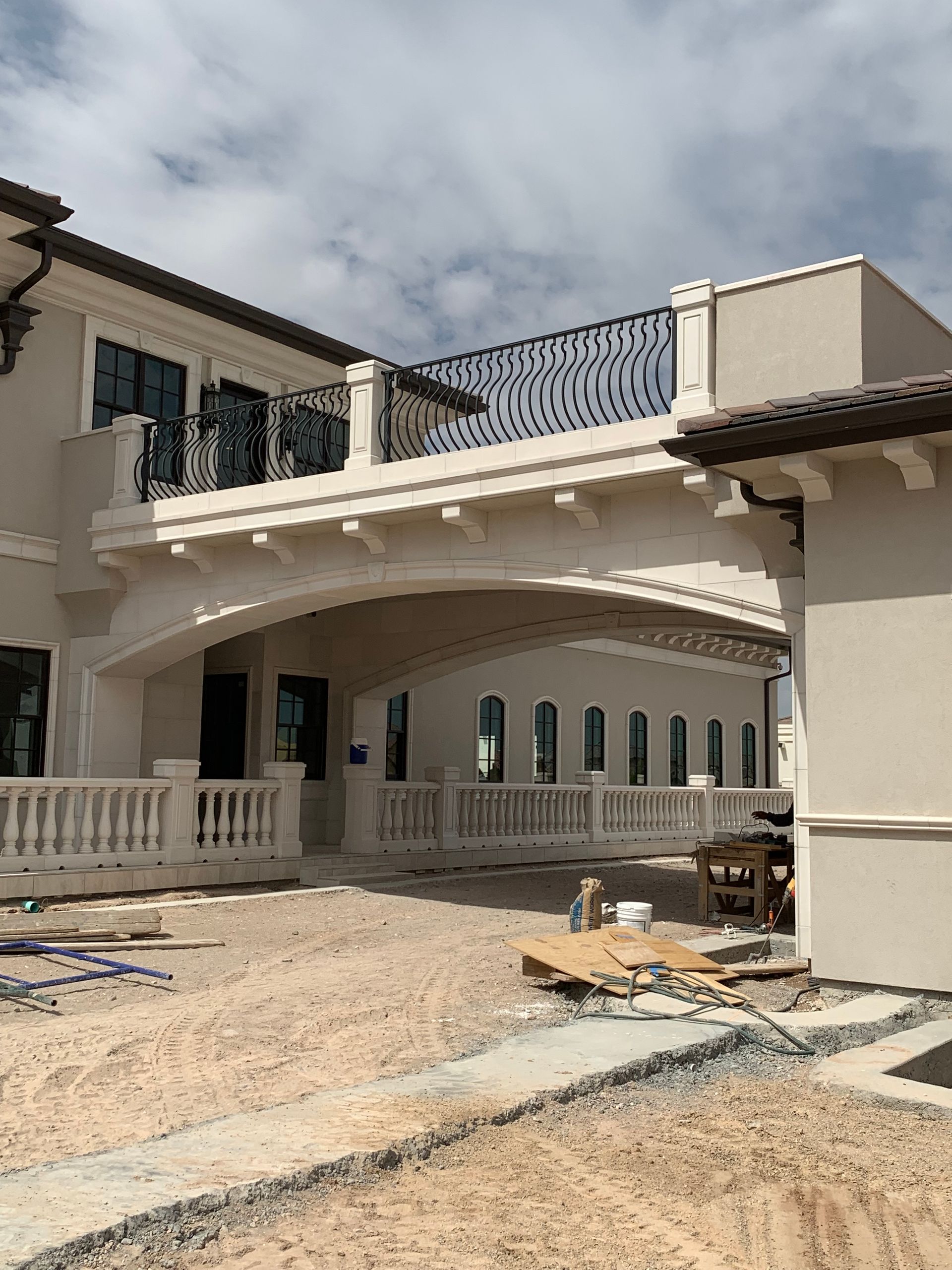 A large white house with a balcony is under construction.