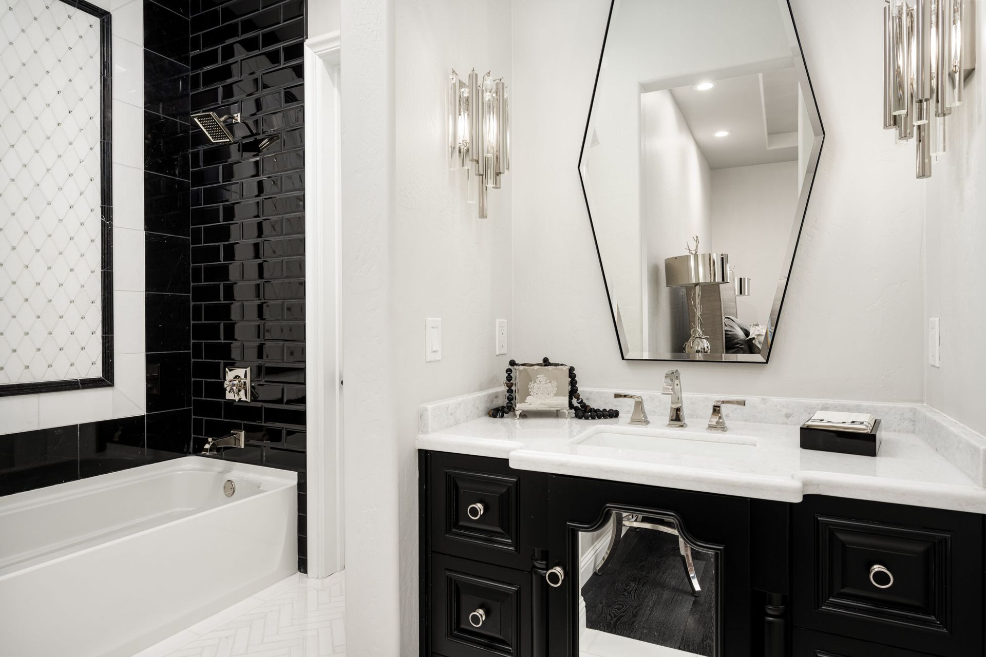A black and white bathroom with a sink , tub and mirror.