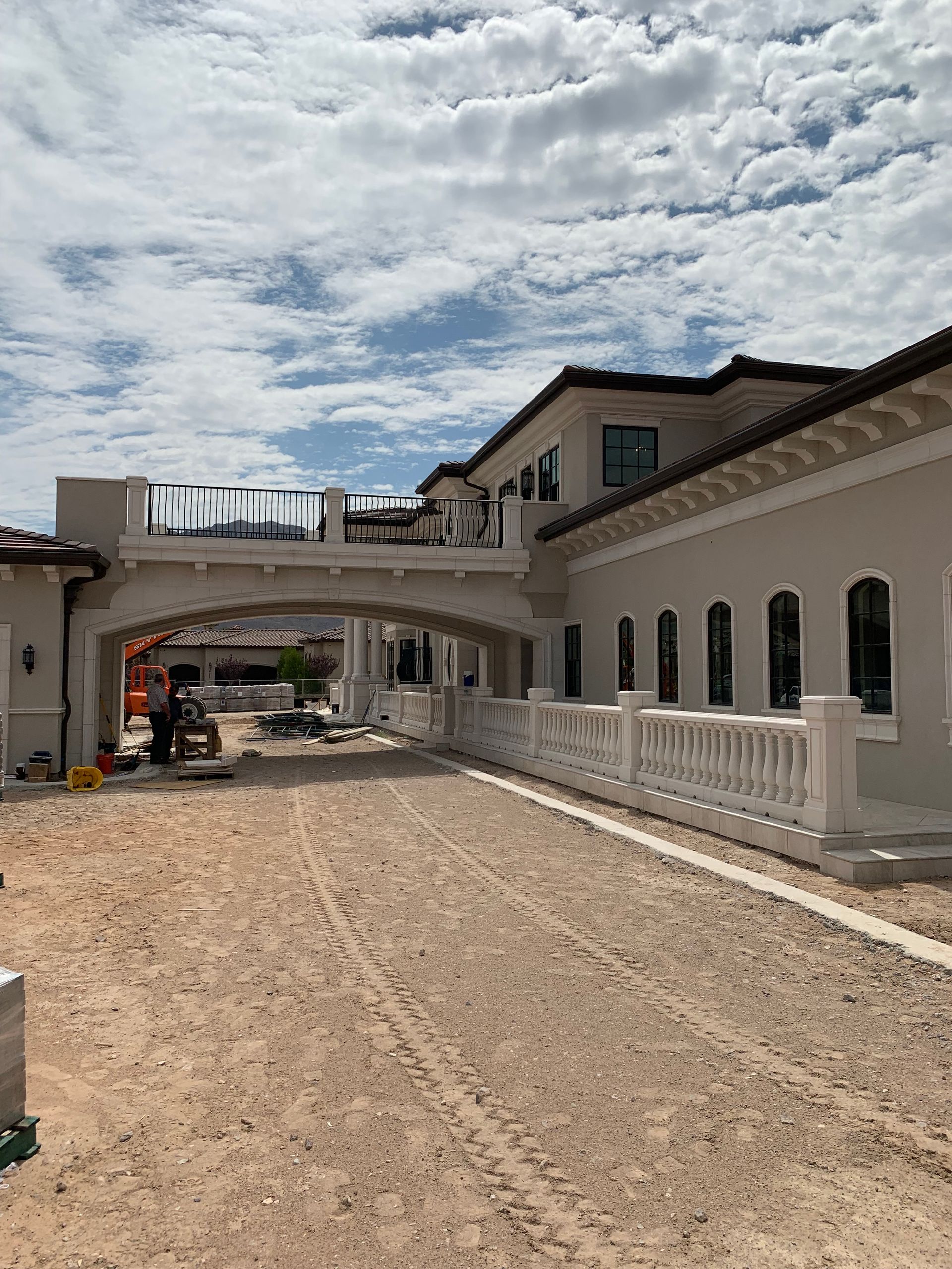 A bridge is being built over a dirt road between two buildings.