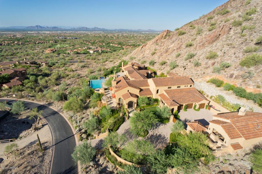 An aerial view of a large house on top of a hill in the desert.