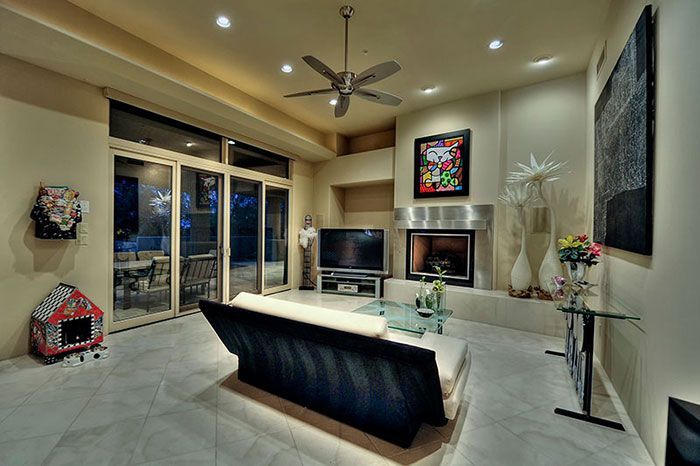 A living room with a couch , television , fireplace and ceiling fan.