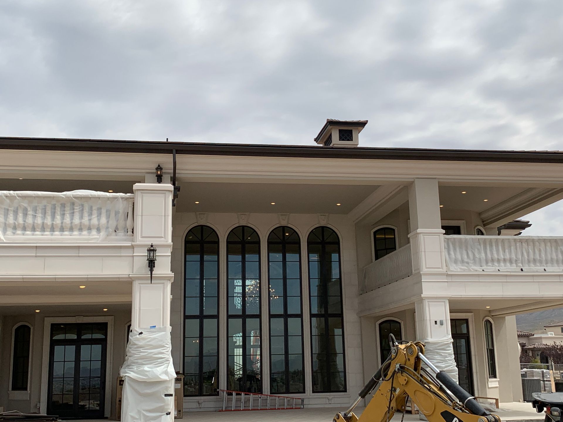 A large white house with a yellow excavator in front of it