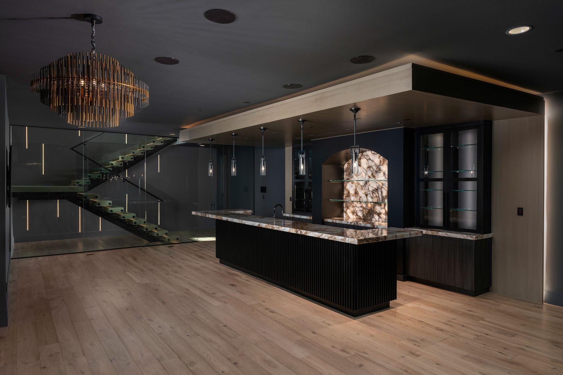 Spacious, modern kitchen with white marble floors, large chandeliers, and sliding glass doors.