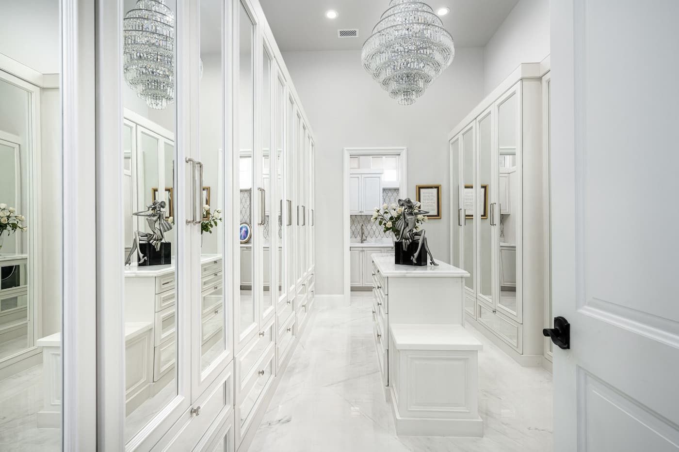 luxury walk-in closet with white mirrored cabinets, wood floor, and chandelier
