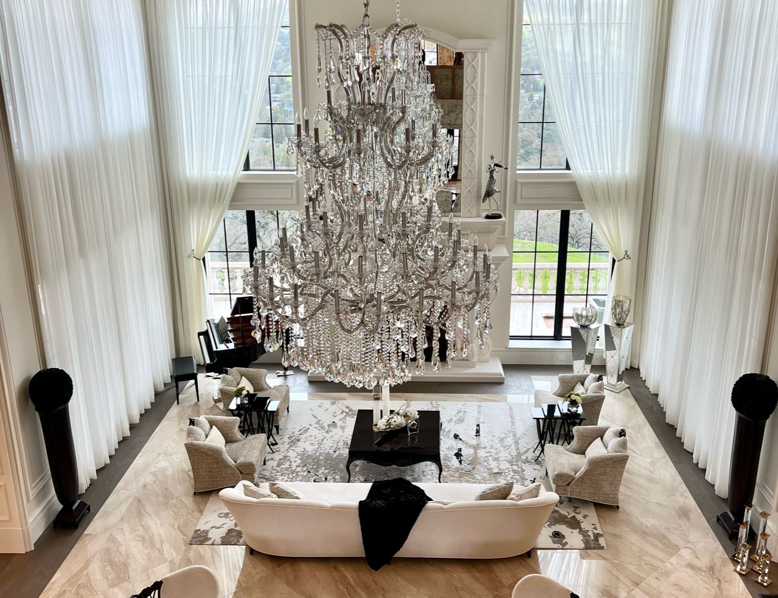 Luxurious open-concept living space with dark wood floors, modern furniture, and a kitchen visible in the background.