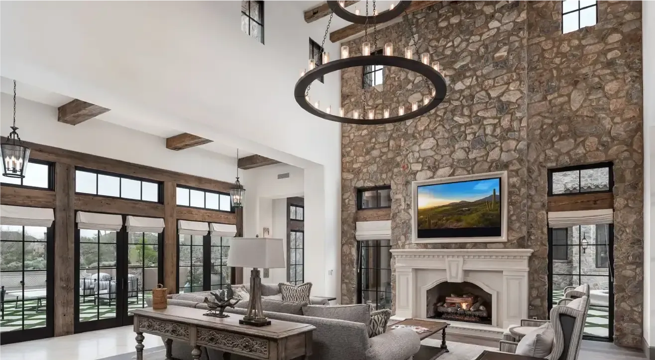 Spacious living room with stone wall, fireplace, large windows, and a chandelier.
