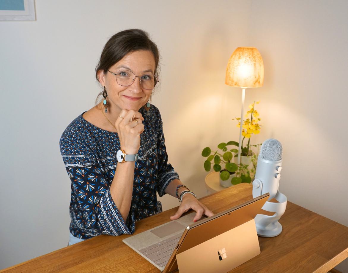 Frau mit Händen vor dem Gesicht vor dem Laptop, wirkt gestresst an einem Schreibtisch.