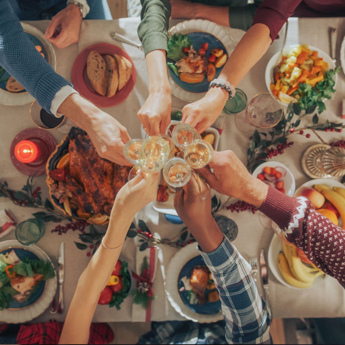 A group of people toasting with wine glasses at a table full of food