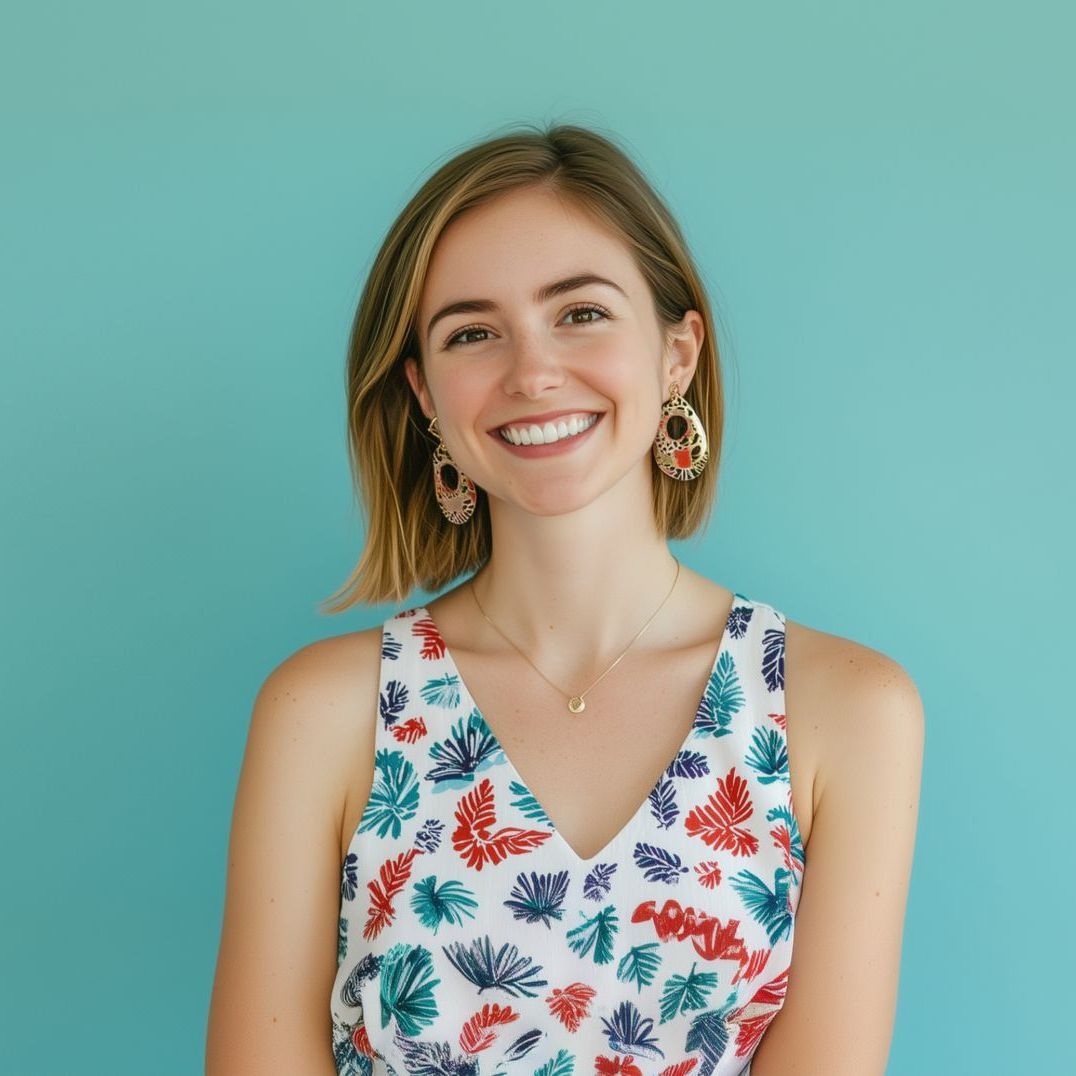 A woman wearing a floral dress and earrings is smiling for the camera.