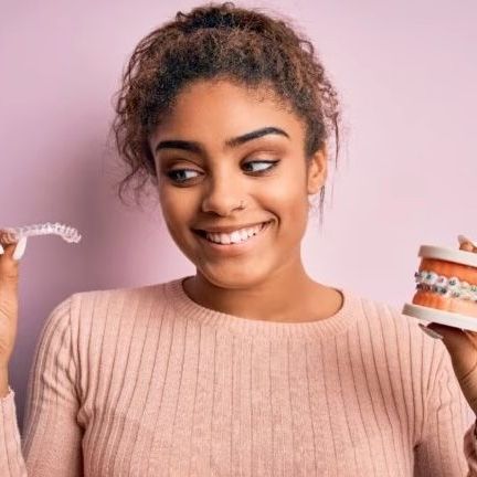 teenage girl  holding an invisalign aligner and a teeth model with braces