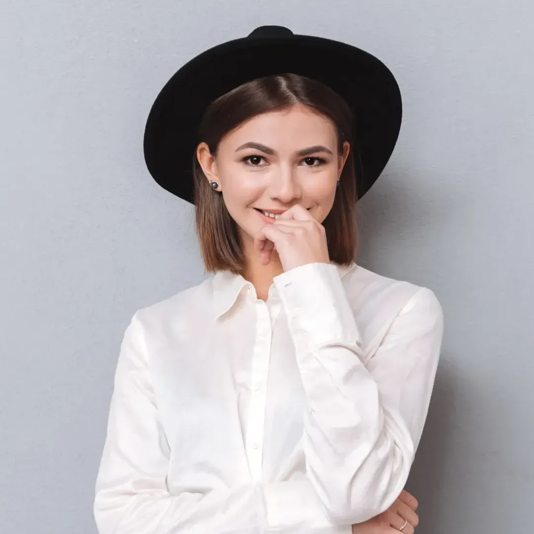 Woman wearing a hat, holding her hand over mouth