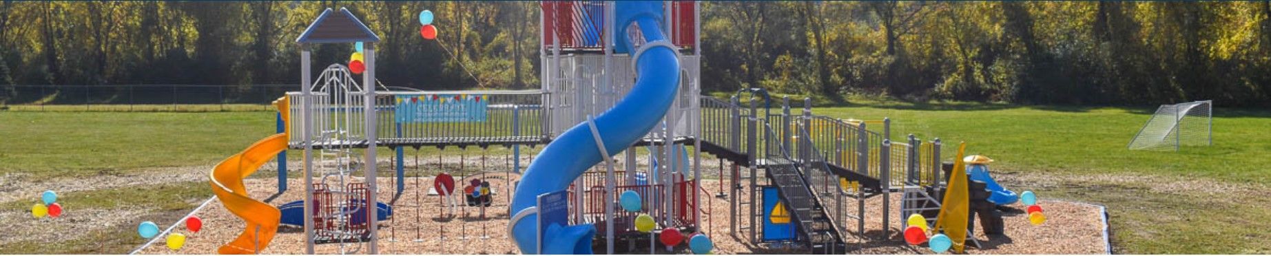 A playground with a blue slide and a castle in the background