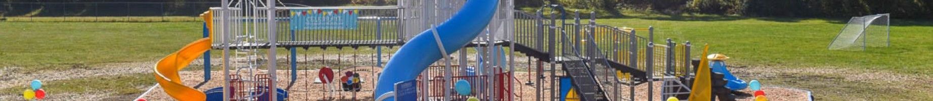 A playground with a blue slide and a castle in the background