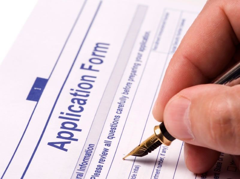 A person is filling out an application form with a fountain pen