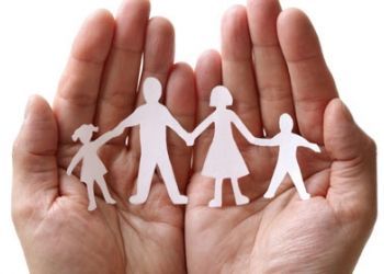 A person is holding a paper cut out of a family holding hands.