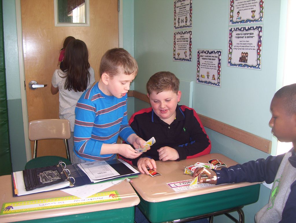 a group of young boys are sitting at desks in a classroom with posters on the wall.