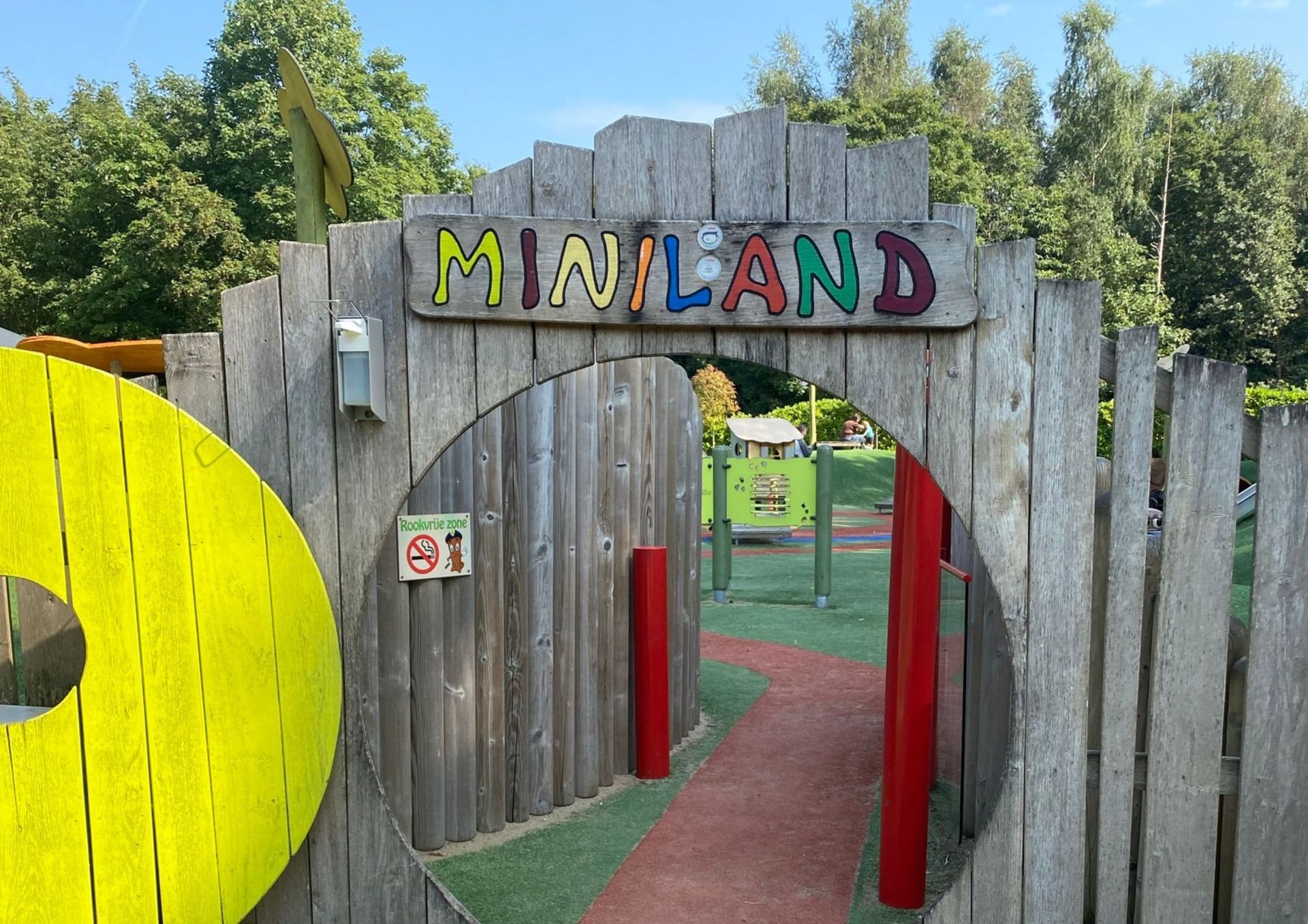 Een houten hek met een bordje met de tekst miniland erop