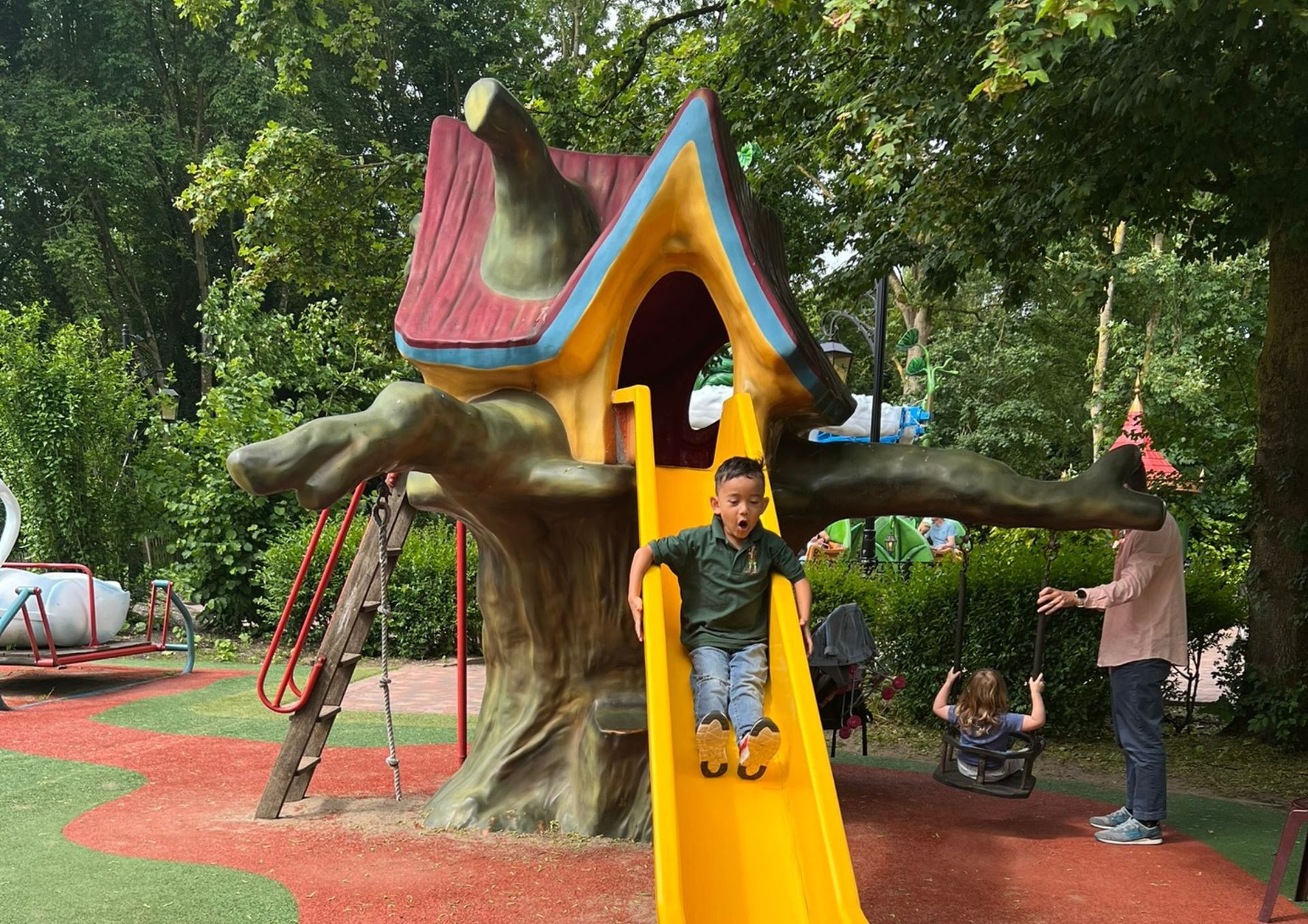 Een jonge jongen speelt op een boomhutglijbaan in een park.