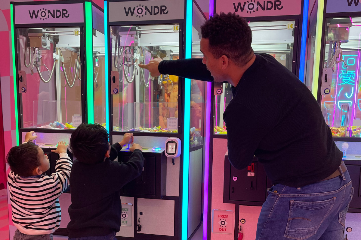 Een man en twee kinderen spelen een spel in Wondr Experience.