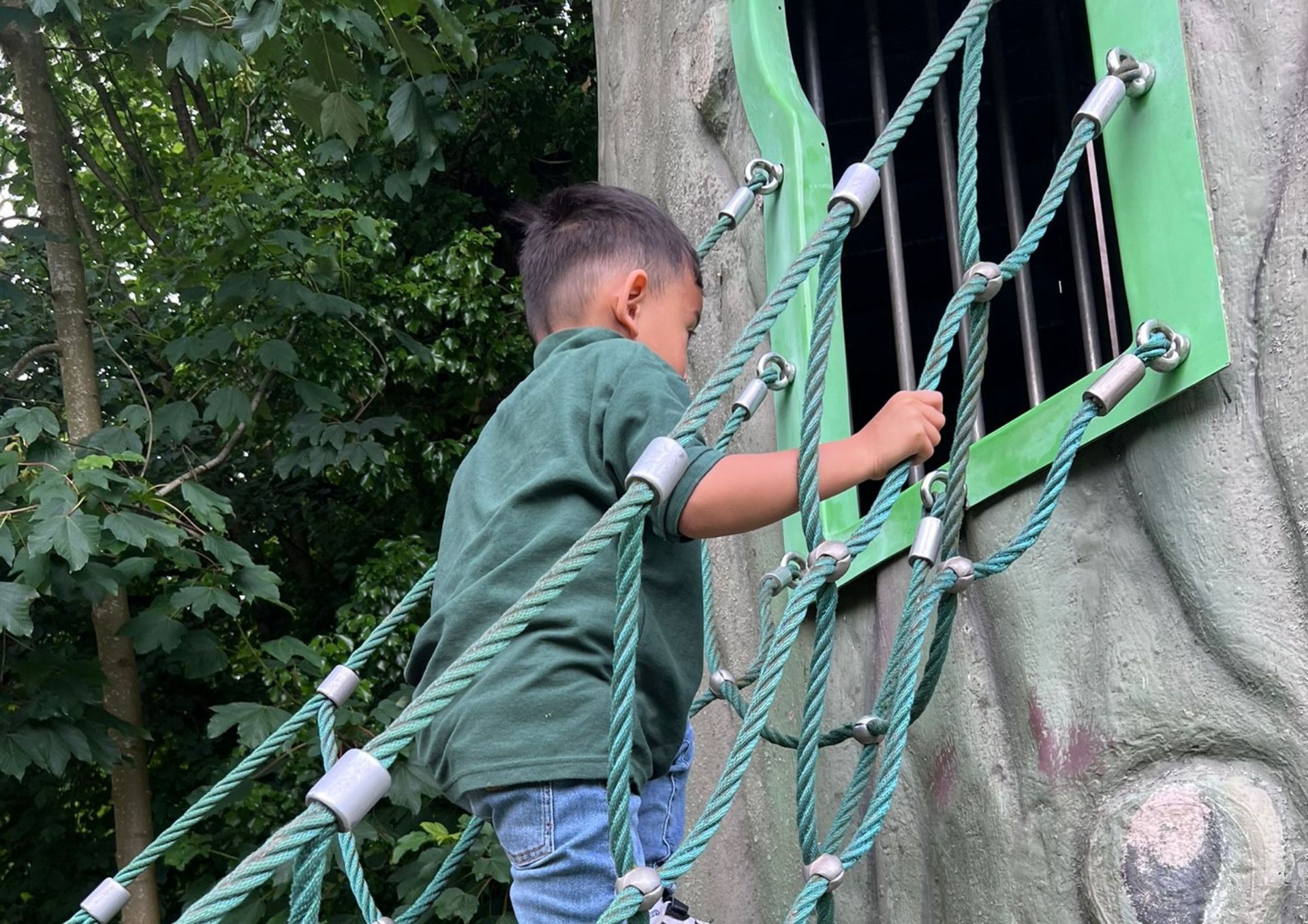 Een jonge jongen speelt op een touwenparcours in een park.