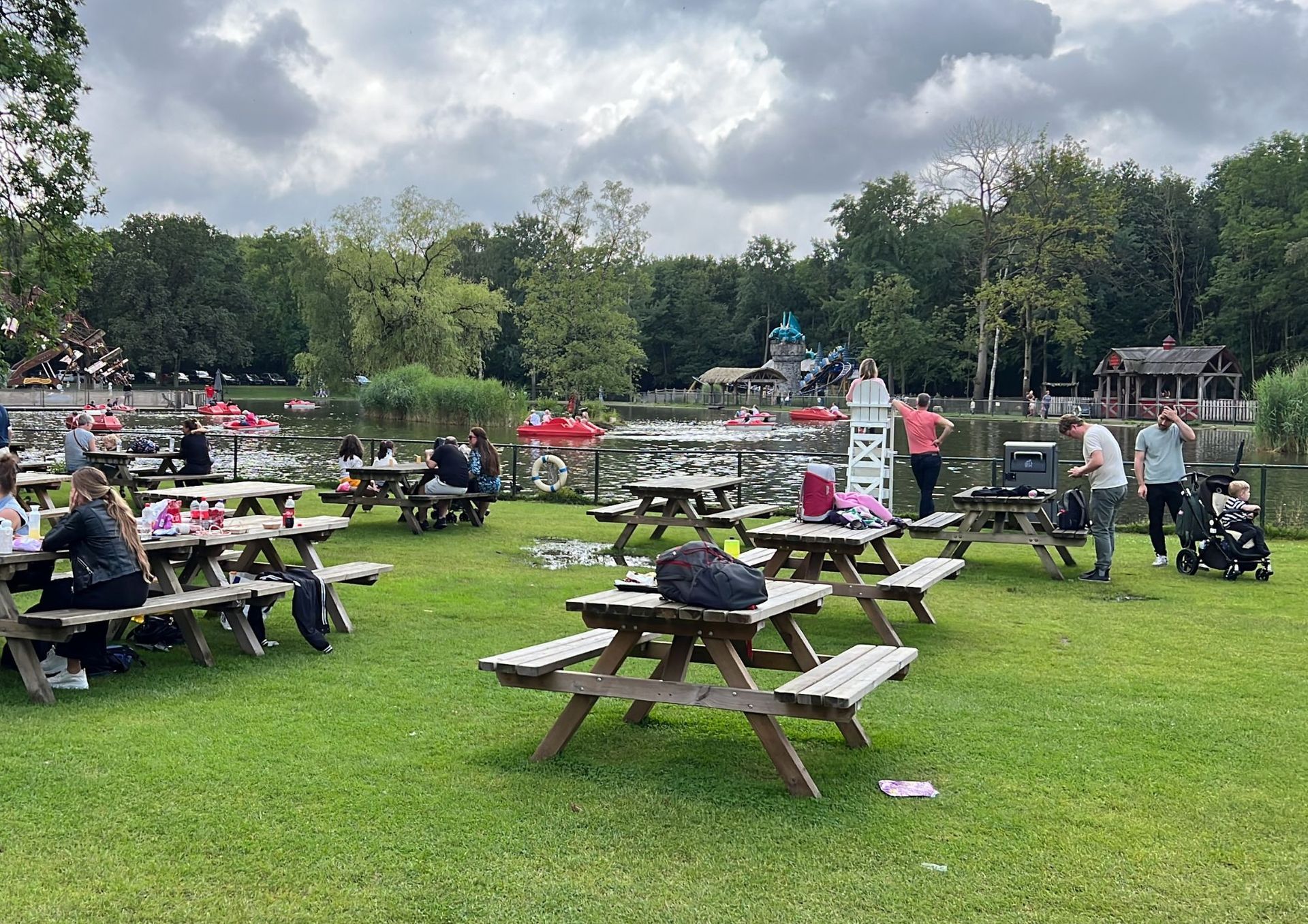 Een groep mensen zit aan picknicktafels in een park.