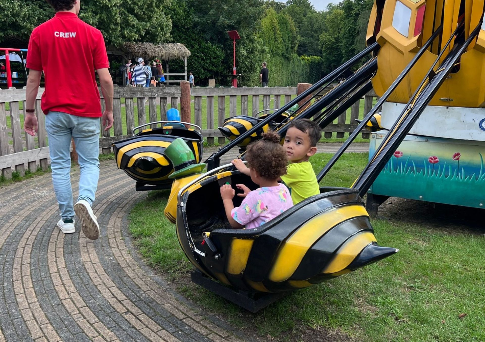 Een man loopt achter een groep kinderen die in een attractie zitten.