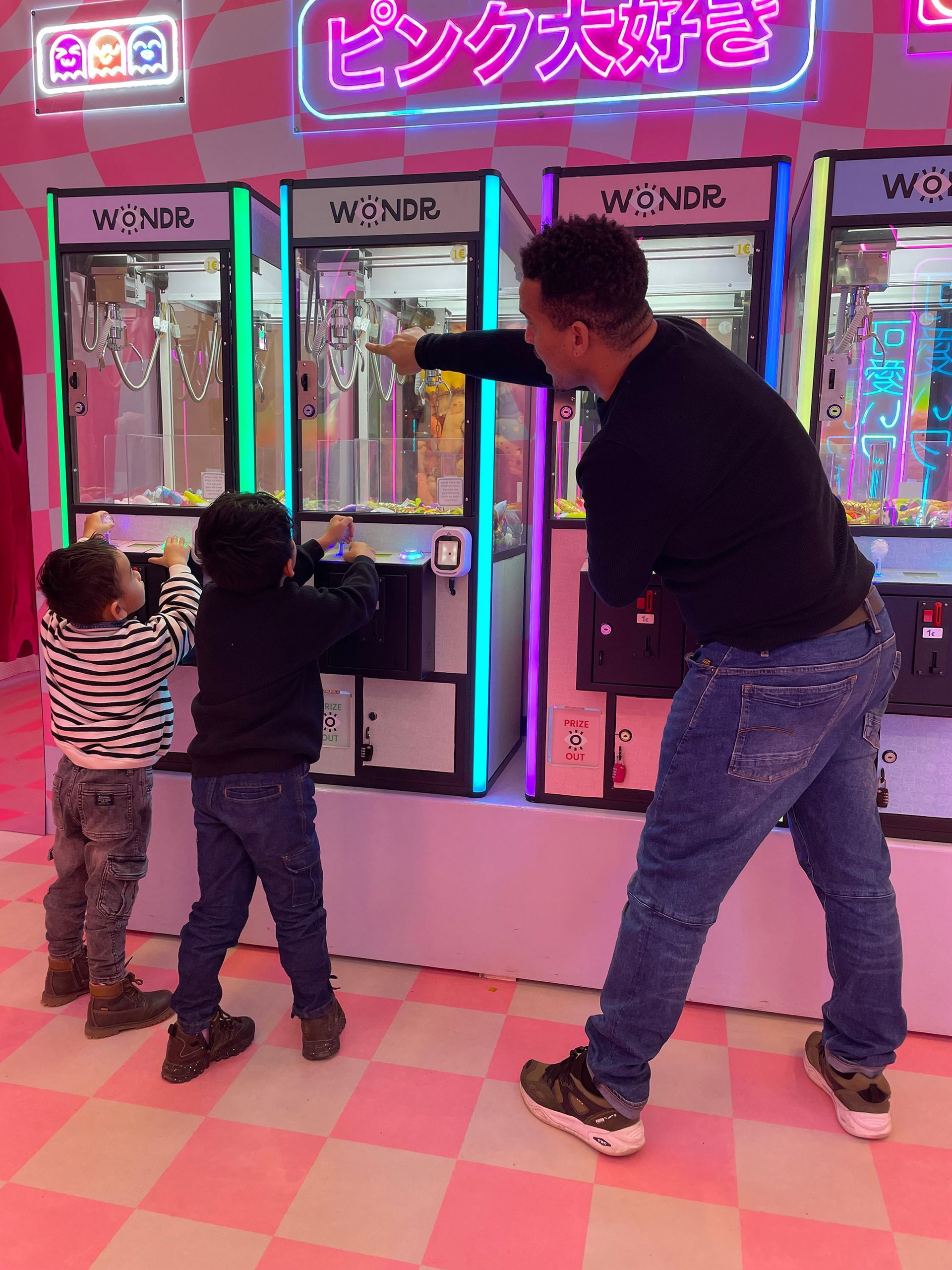 Een man en twee kinderen spelen een spel in een pretpark.