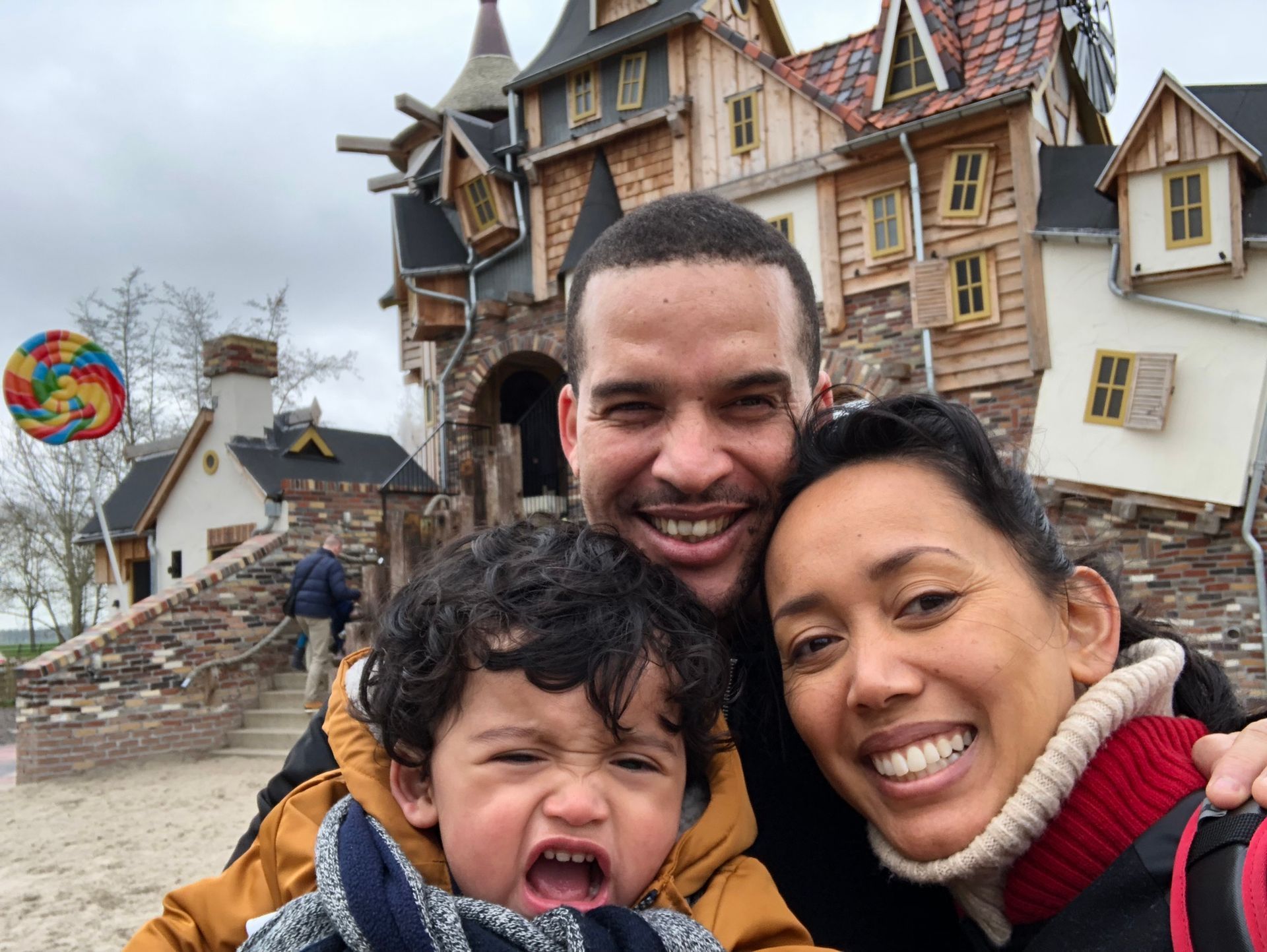 Een man, vrouw en kind poseren voor een foto voor een kasteel.