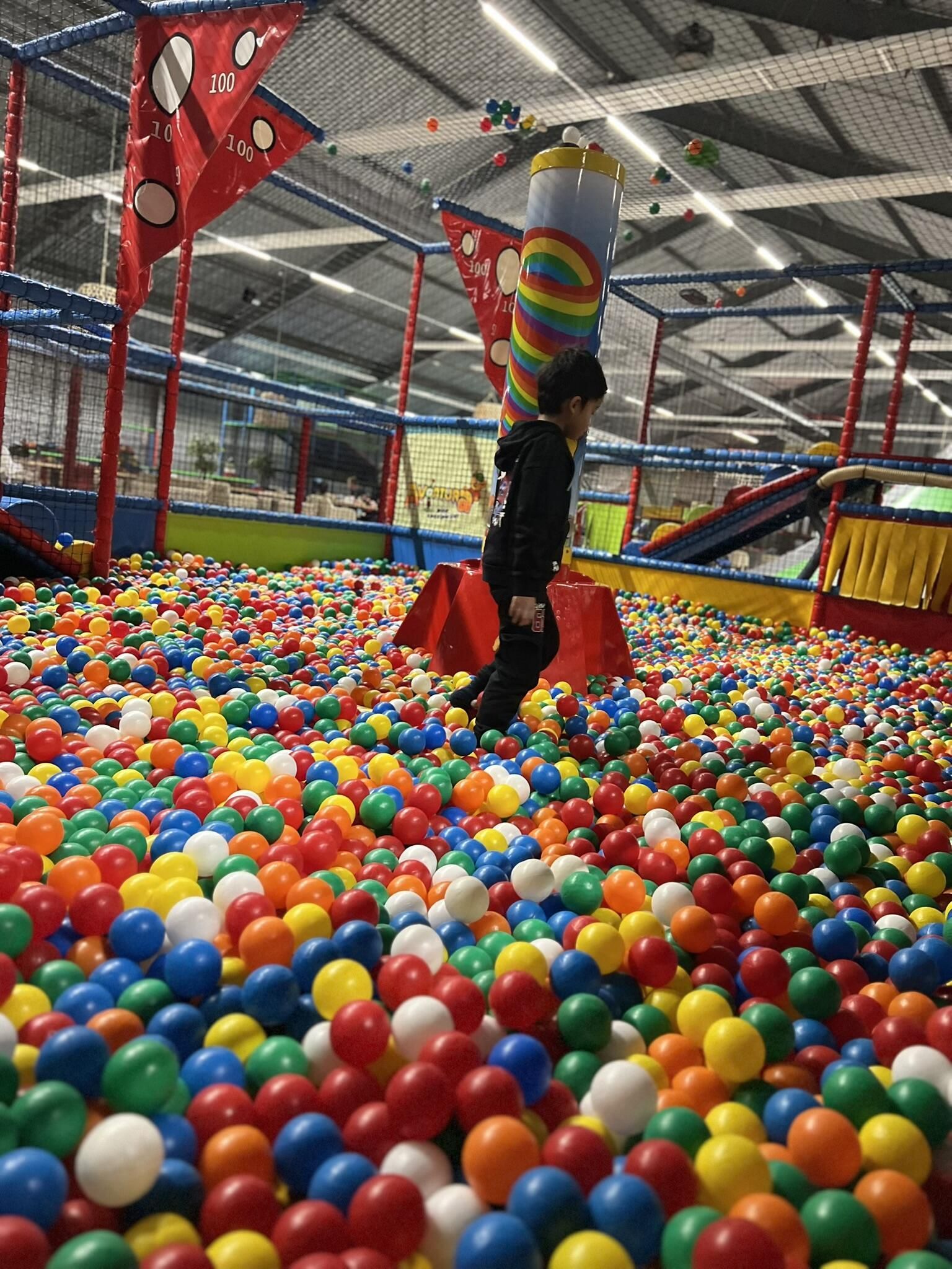 Een kind speelt in een ballenbak gevuld met gekleurde ballen.