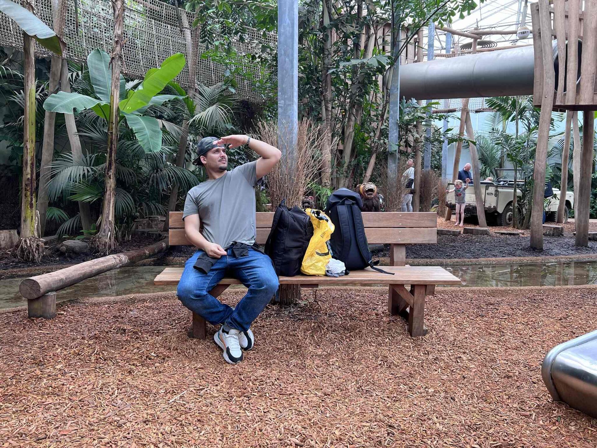 Een man zit op een houten bank in een park.