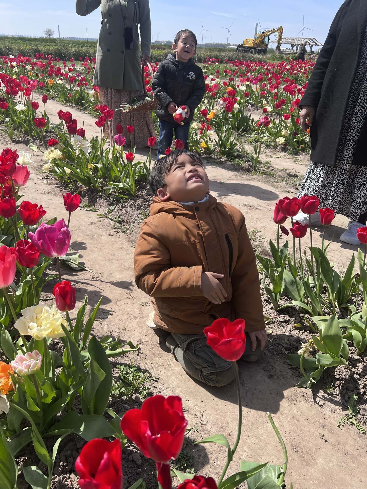 Een vrouw houdt een kind vast in een bloemenveld.